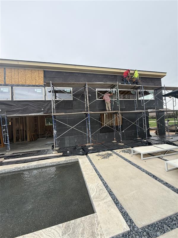 Phase 20 — Poolside elevation nearly wrapped, scaffolding still in place for finish work