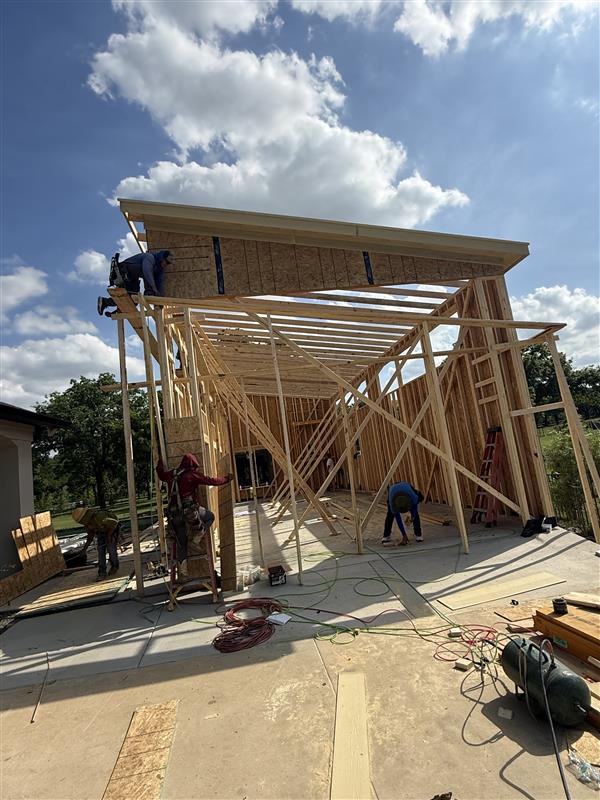 Phase 9 — Rear framing complete with roof rafters overhanging the slab