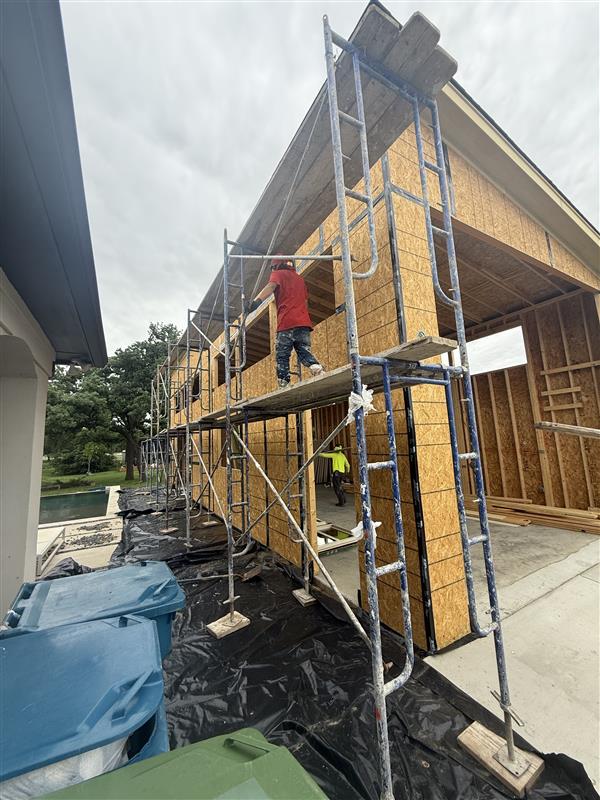 Phase 17 — Scaffolding staged along the OSB-clad exterior for weather barrier install