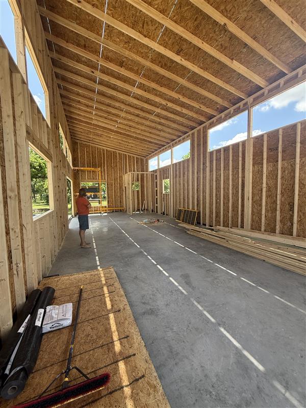 Phase 14 — Interior view showing vaulted ceiling with OSB roof decking and framed window openings