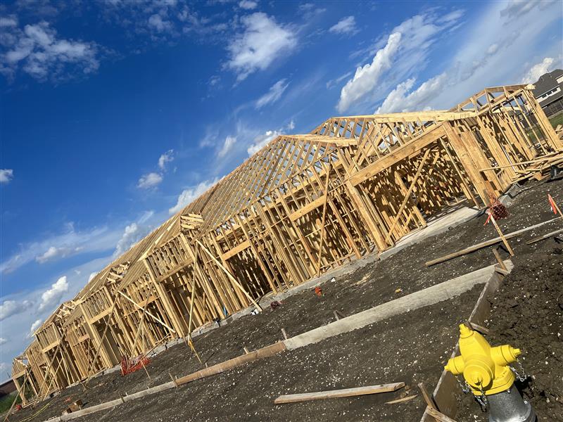 Framing phase: wood trusses and wall framing running the length of the building
