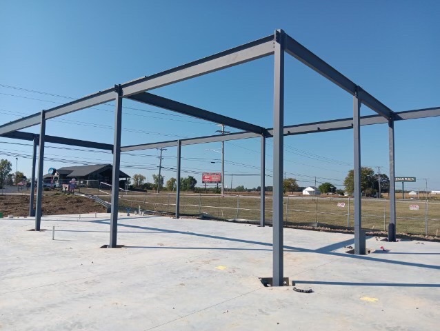 Phase 1 — Structural steel frame erected on slab: columns, beams and roof structure in place