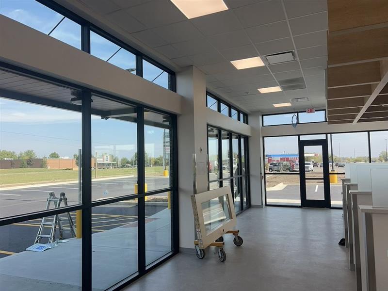 Phase 8 — Dry-in: storefront glazing and entry doors installed at the customer-facing elevation