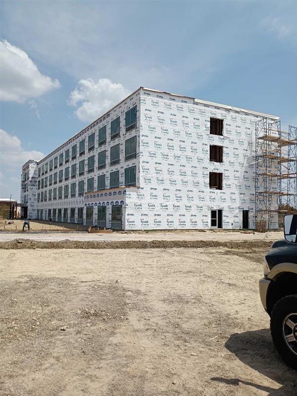 Phase 5 — Full building wrapped in Tyvek weather barrier with window openings cut in