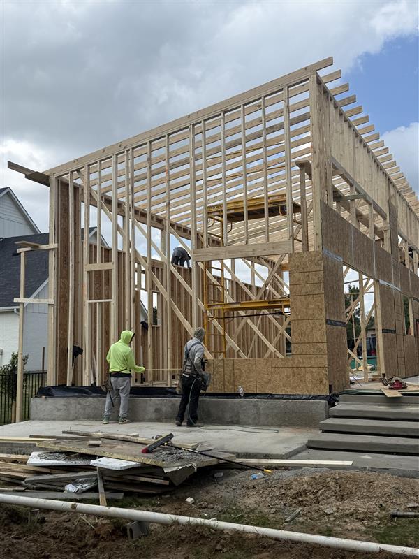 Phase 10 — Roof framing extended with crew setting rafters overhead