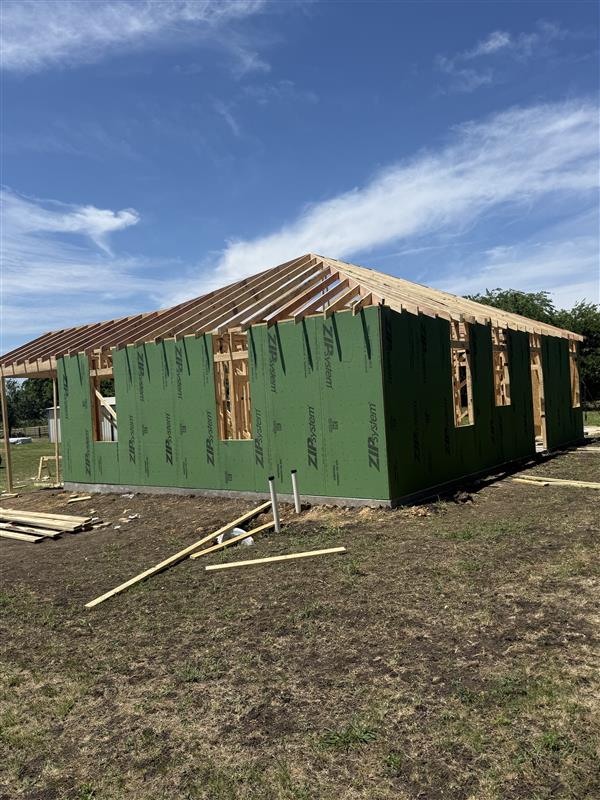 Phase 5 — Roof rafters set over sheathed walls with covered porch framed