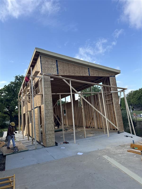Phase 15 — Exterior corner with roof structure complete and scaffolding set for sheathing