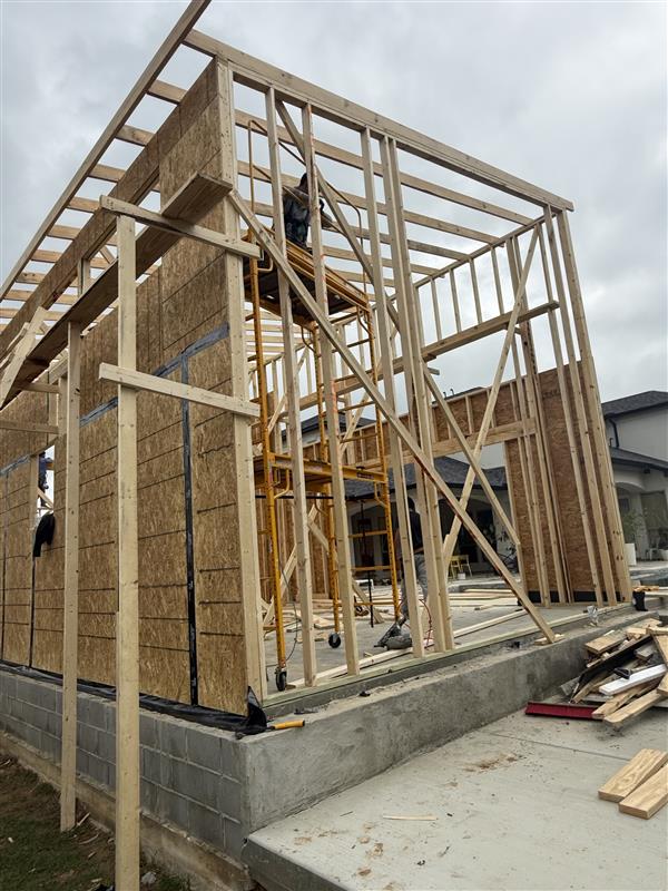 Phase 13 — Side elevation fully sheathed with roof decking in progress