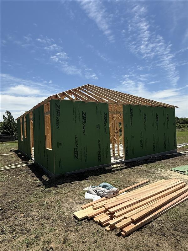 Phase 8 — Full building wrapped in ZIP System with hip roof framing in place