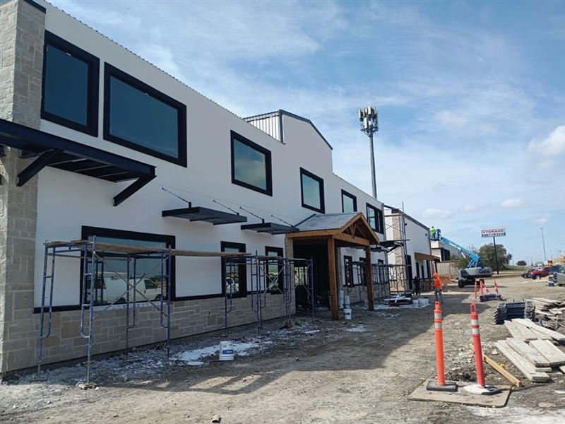 Phase 9 — Exterior finishes going on: stucco, black window trim and timber entry canopy taking shape
