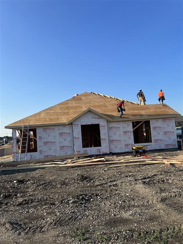 Roof decking: crew running sheathing over hip roof at end of building